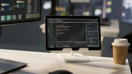 Programming language on digital device screen in empty IT department office used for app development. Close up of tablet left open on desk in tech startup company workspace with nobody in
