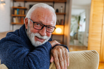 Cheerful elderly man leaning on sofa at home