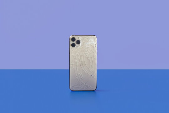 Silver coloured smartphone with cracked touchscreen and triple camera