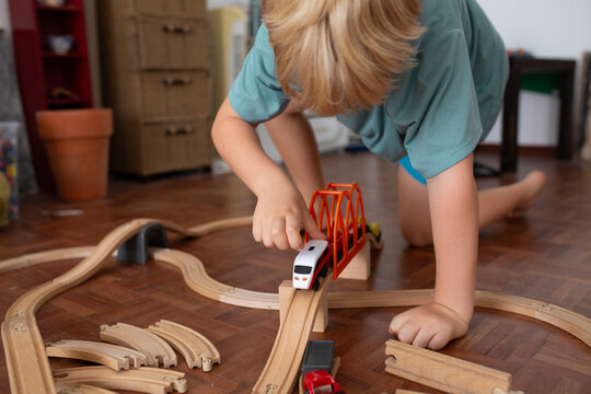 Boy playing with wooden tracks and trains