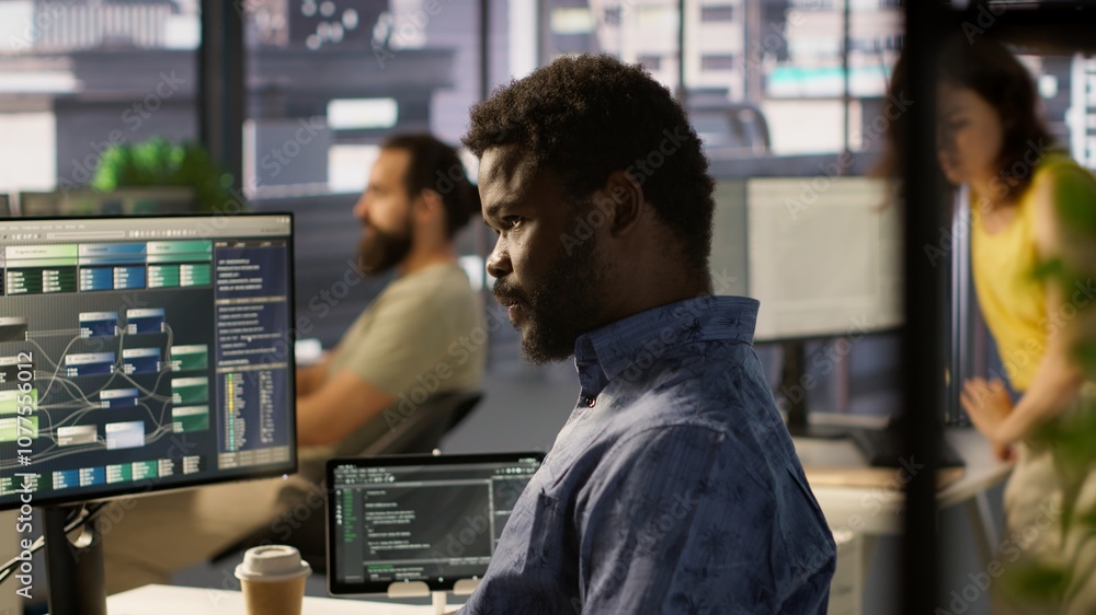 Poster programmer waiting for coworker to come help him fix applications issues, dealing with databases and