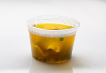 Plastic container with wonton soup from Chinese takeout restaurant on white background