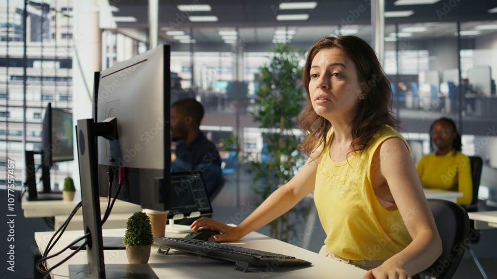 Poster worker sitting at office desk using computer during job shift, being interrupted by manager to recei