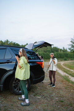 Women put trekking poles in the car trunk