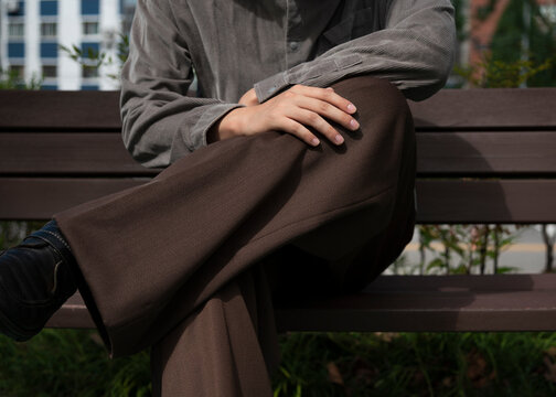 Man sitting on the chair with brown pants and gray shirts 