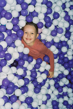Adorable girl has fun in ball pool.