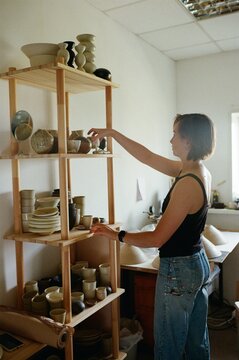 Artisan Arranging Pottery in a Sunlit Studio