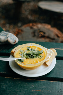 Pumpkin cream soup with a piece of bread on a wooden table