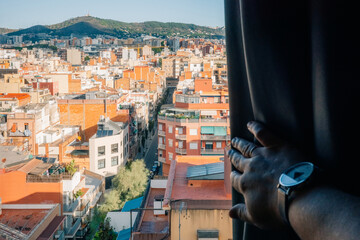 View of a cityscape from a window with a hand pulling back the curtain