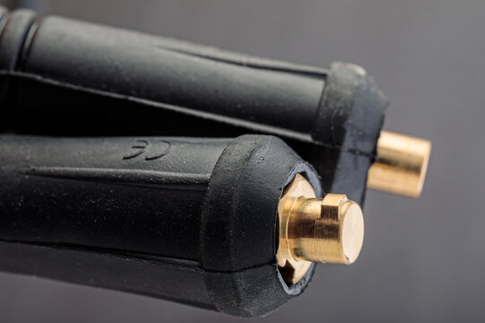 Close-up of cable plugs of an electrode holder and grounding clamp from a welding inverter machine, showing fine details of industrial connections.