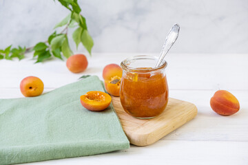 Homemade apricot jam in glass jar on kitchen white background. Summer harvest and canned food. 