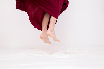 Woman jumping on bed with red dress