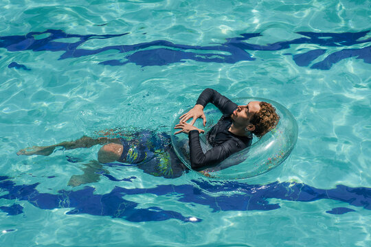 Young man in a pool with a float