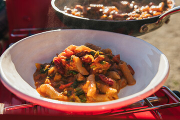 Cooking gourmet pasta with beans and red tomato sauce on a trip