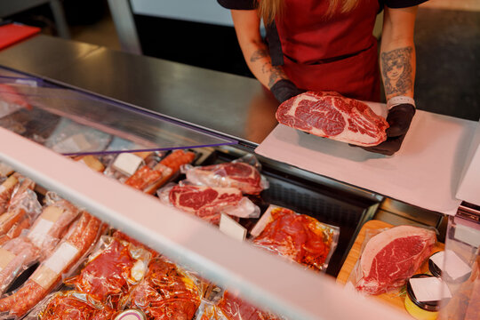 A skilled butcher expertly handling and preparing premium cuts of meat in a modern, vibrant market setting - Powered by Adobe