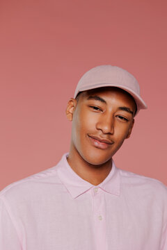 Man wearing pink shirt and cap smiling on pink background