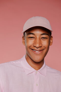 Man wearing pink shirt and cap smiling on pink background