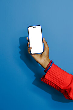 Woman holding smartphone with blank screen on blue background
