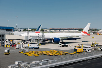 Aircraft parked at JFK airport gate with ground support vehicles