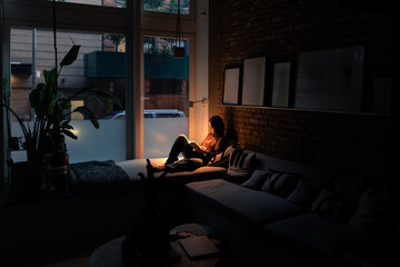 Woman relaxing at night reading a book on her bed in her New York Loft