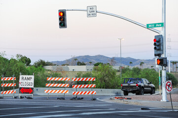 A 'Ramp Closed' sign and orange-and-white striped barricades with a detour arrow block access to a...