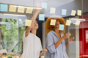 Team brainstorming session with sticky notes on glass