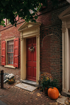Red Brick House with Pumpkin and Flowers by the Door
