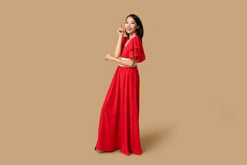 Beautiful young happy Asian woman on brown background. Chinese New Year celebration
