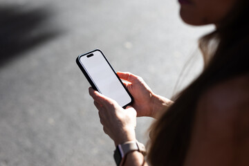 Hands of an anonymous woman using her smartphone during a sunny day