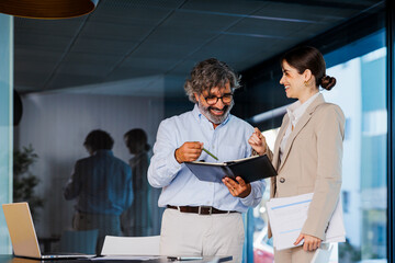 Businesspeople having informal meeting reading notes in notebook