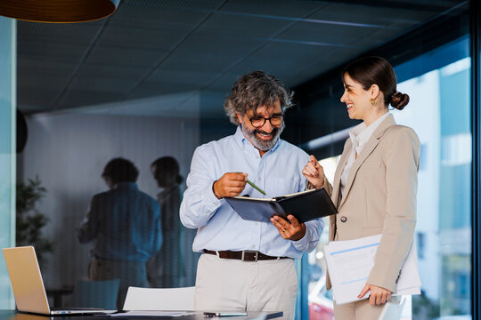 Businesspeople having informal meeting reading notes in notebook