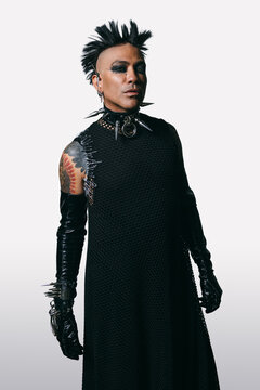Edgy punk fashion man with spiked accessories and bold makeup on white