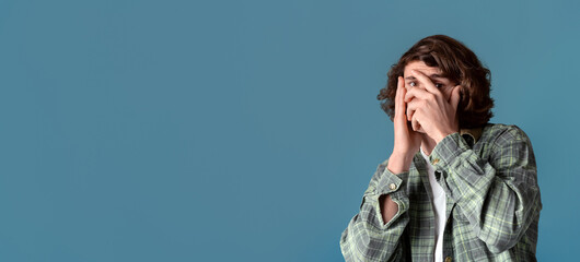 Anxiety and stress concept. Curly guy closing his face in fear on color background