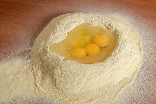 Whole wheat flour on the table with eggs for making pasta 