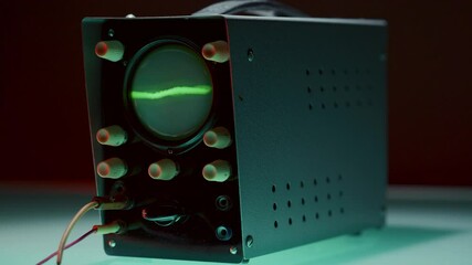 Old-fashioned wired oscilloscope displaying rapidly fluctuating waveform with chaotic amplitude. Close-up shot