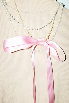 Turtleneck and shiny pearl necklaces & silk ribbon bow and flashlight