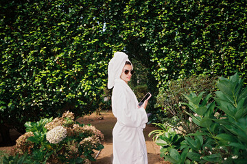 UGC portrait of woman with bathrobe and sunglasses in the garden
