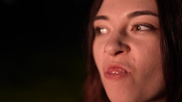 Woman is picking in teeth by nail finger trying to get stuck pieces of food after meal filmed in closeup and slow motion. Macro of female face doing dental hygiene procedure by hands in the evening