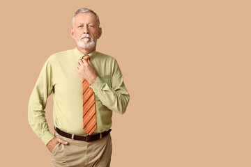 Handsome mature man with stylish tie on beige background