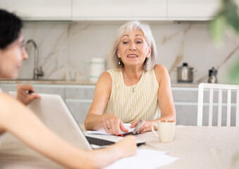 Mature woman consulting with female real estate agent in home interior
