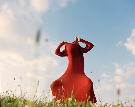 Surreal Artistic Photo of Figure in Red Dress in Meadow