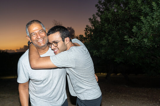 Father and Teen Son Share a Joyful Moment in the Park at Sunset