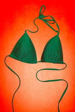 Green triangle bikini top on red background and hard direct flashlight