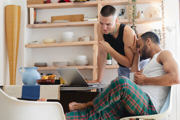 Gay couple sharing a lighthearted moment while using a laptop