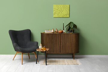 Interior of living room with armchair, commode and decorative pumpkins