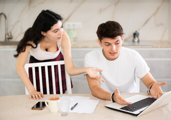 Sad and tired freelancer husband works at home on laptop and listens to her wife reproaches in frustration. Family quarrel, lack of free time, unmet needs