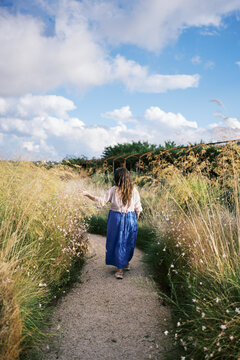Woman walking on a serene path in a nature field area