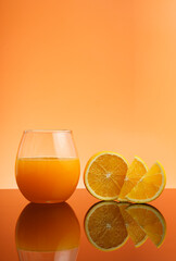 vertical photo of glass of fresh orange juice on reflective table, Fresh fruits Orange juice in glass with group of orange on white background, isolate orange background