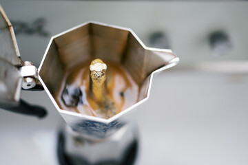 Espresso bubbling in moka pot during brewing process, close-up.
