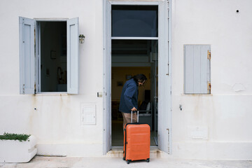 Traveler wheel in an orange suitcase into a house